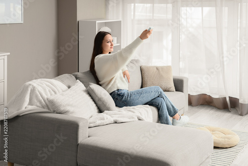 Home entertainment and leisure, young woman using remote control to operate a...