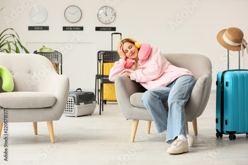 Travel fatigue and airport delay, young woman sleeping in lounge chair with n...