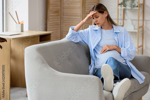 Pregnancy stress and prenatal anxiety, tired pregnant woman sitting on sofa f...