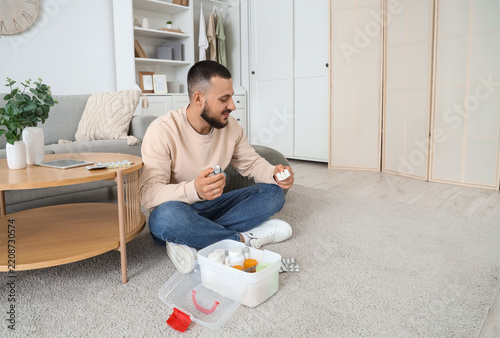 Healthcare management and medication routine, man sitting on floor at home or...