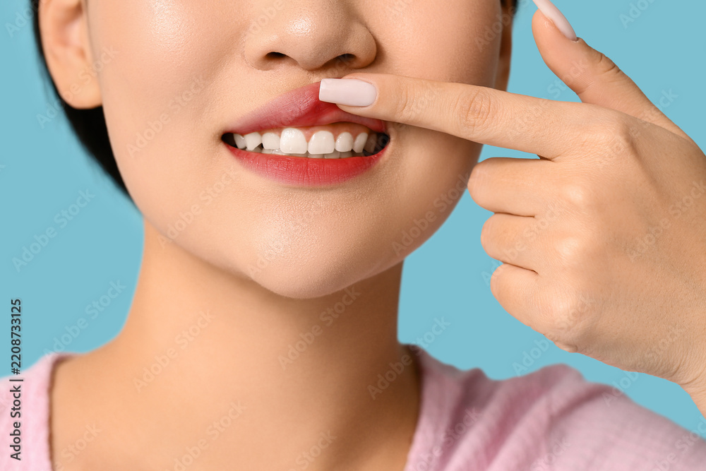 Obraz premium Dental health and oral hygiene, young woman checking teeth and gums for dental care and oral examination on a blue background