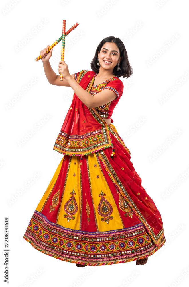 Fototapeta premium Beautiful Indian woman in traditional Chaniya Choli dancing with Dandiya sticks for Navratri festival. Vibrant ethnic attire for Garba dance, isolated on transparent background for design.