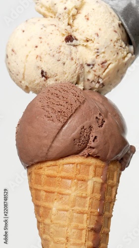 4K footage Metal ice cream scoop placing scoop of chocolate chip ice cream on top of chocolate ice cream cone isolated on white background.