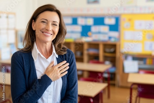 Smiling female teacher with hand on heart in classroom expressing gratitude