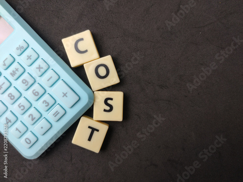 Letter tiles spelling COST are positioned next to a blue calculator on a dark background