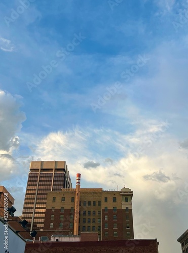 Urban City Skyline With Brick Buildings, Chimney Tower and Blue Sky Clouds Over Downtown