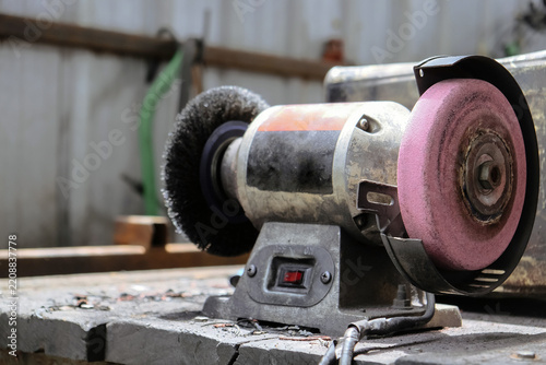 Bench grinder sitting on a workbench in a workshop, ready for metalworking