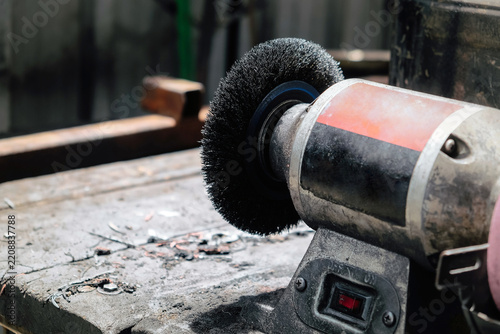 Bench grinder sitting on a workbench in a workshop, ready for metalworking