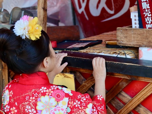 Naklejka 七五三の着物姿の女の子が日本の神社の出店で商品を待つ手元のクローズアップ、横構図