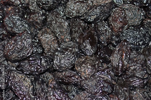 Detailed close-up shot of multiple prunes, showcasing their deep, rich black color and wrinkled texture, emphasizing their natural, sweet, and chewy characteristics.
