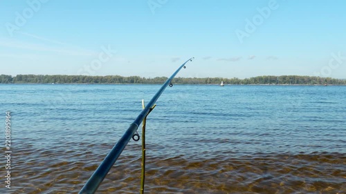 Fishing rod waiting for a bite on a calm river bank