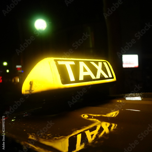 Obraz na plátně Yellow taxi cab top light glowing at night with hood reflection