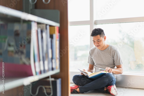 male asian student studying and reading book in library