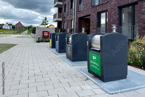 Modern recycling bins line the pathway in a residential area