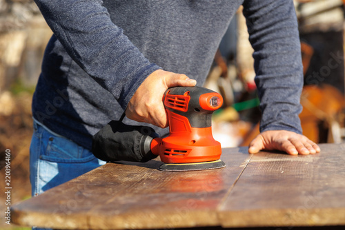 Fotografie DIY Furniture Repair Using Power Sander on Worn Wooden Table