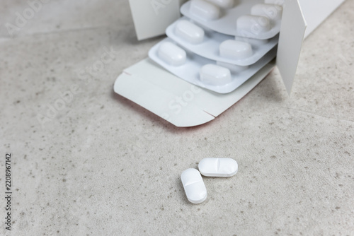 White tablets and blister packs on concrete surface with medical and healthcare concept.