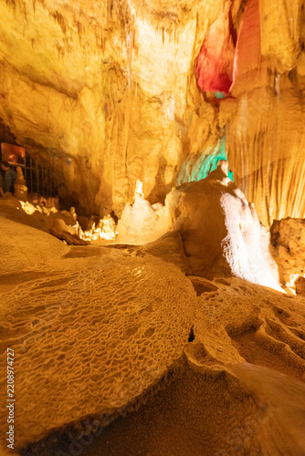 Fotografie Stalactites and stalagmites in a brightly lit cave with interesting rock formati