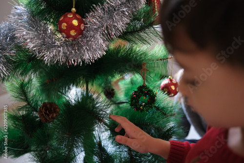 Children decorating christmas tree with ornaments for holiday season