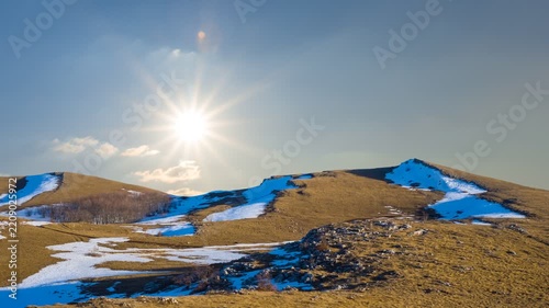 mountain chain in snow under a sparkle sun time lapse scene