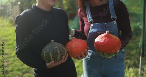 Mother and son holding organic pumpkins at vegetable home garden - Family people having fun during autumn season - Fall lifestyle concept - UGC wide lens content