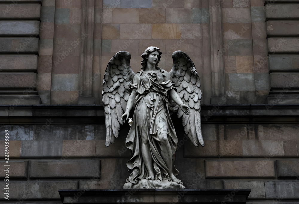 Fototapeta premium Spirituality and religion concept stone angel statue with wings on a historic building mourning and peace architectural detail in the city