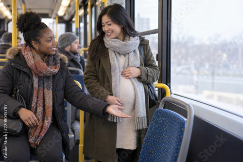 Kind black woman giving up her seat to pregnant asian woman on crowded winter bus, courtesy in public transport
