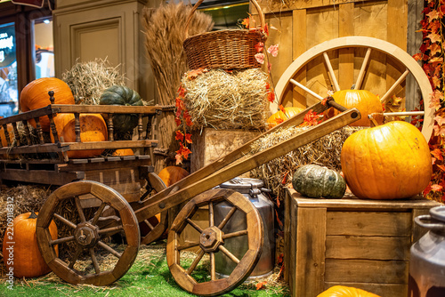Autumnal decorative arrangement featuring pumpkins and a wooden cart, reminiscent of a harvest festival display.