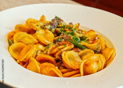 Orecchiette pasta (shaped like little ears) with a tomato-based sauce, meat (similar to sausages or a ragout), herbs and green beans or cabbage.