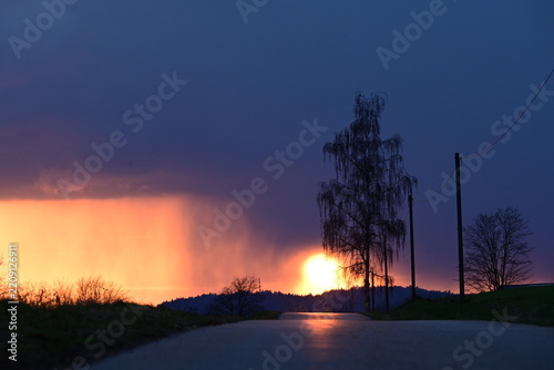 Dramatischer Sonnenuntergang kurz nach einem Gewitter auf einer Landstraße