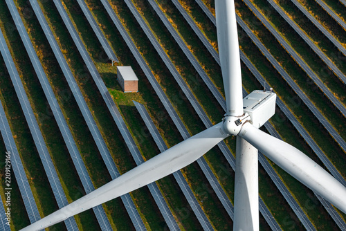 Aerial view of Chelveston Renewable Energy, BESS, featuring a large wind turbine and rows of solar panels in the green landscape of Chelveston, England, United Kingdom.