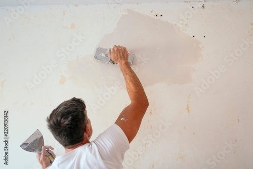 Man repair wall with plaster during home renovation