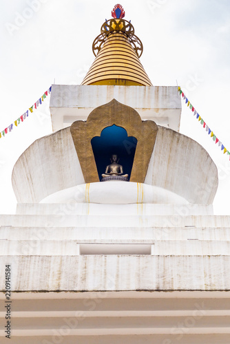 Buddhist stupa with meditation statue and prayer flags