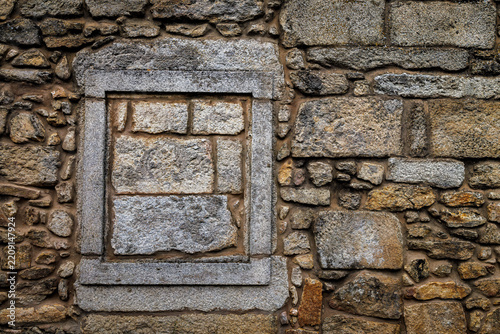 Old sealed opening framed with granite blocks in a rustic stone wall.