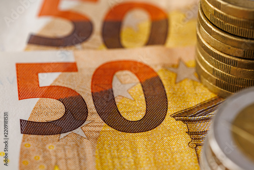 Close-up macro of fifty euro banknotes with stacked euro coins, shallow depth of field, finance, savings, inflation and European economy concept