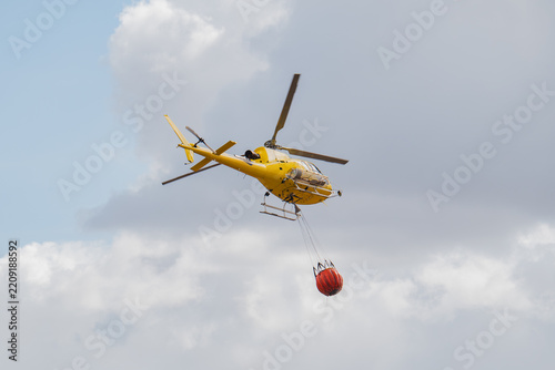 Firefighting helicopter release water drop over wildfire zone