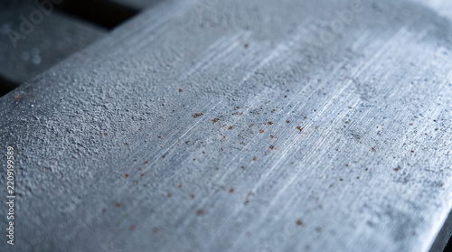 Close up perspective texture of light grey brushed metal surface with fine scratches and tiny rust specks
