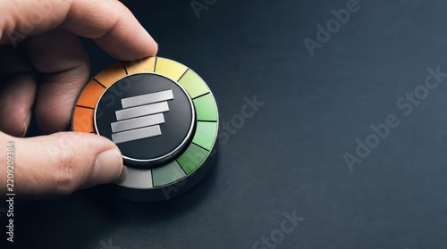 risk management insurance forecasting. Hand adjusting a circular gauge with colored segments from red to green on a dark surface.
