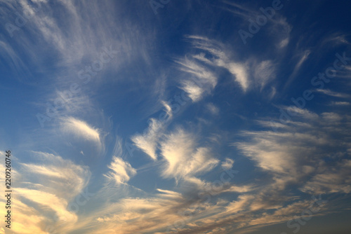 Golden sunset clouds floating in blue sky at dusk 