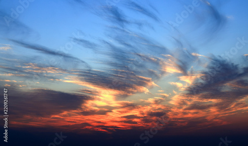 Golden sunset clouds floating in blue sky at dusk 