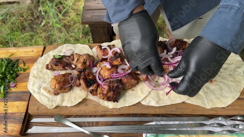 Pieces of hot, juicy shashlik served on lavash are sprinkled with sliced ​​red onion. High quality 4k footage
