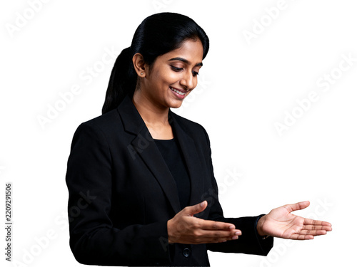 Poised Indian professional, warmly smiling in a black suit, thoughtfully presenting with open hands, an isolated transparent cutout