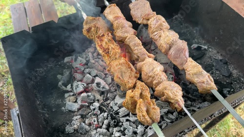 Shashlik on the grill a skewer with pieces of pork is being turned over the coals. High quality 4k footage