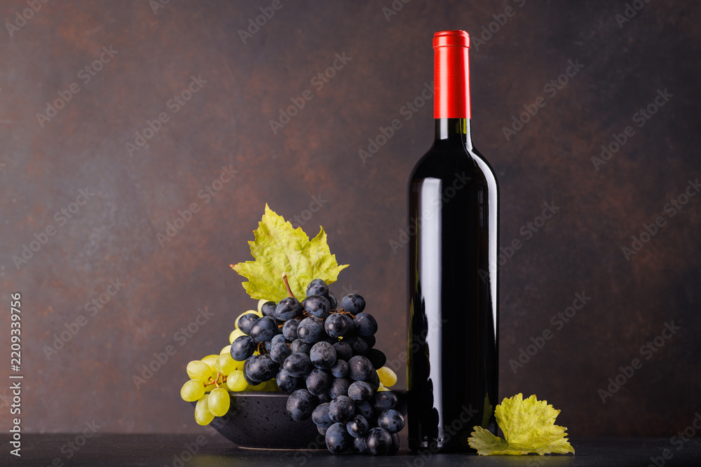 Obraz premium Red wine bottle with a glass and basket of fresh grapes