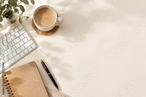 Coffee Cup, Notebook, and Keyboard on a Desk With Sunlight