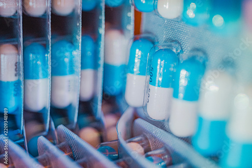 Blue and white pharmaceutical capsules arranged in laboratory trays, illustrating medicine production, pharmaceutical research, healthcare technology, and drug manufacturing.