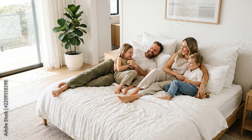 Cheerful family relaxing together in a bright comfortable bedroom perfectly reflecting warm domestic affection and loving bonds concepts