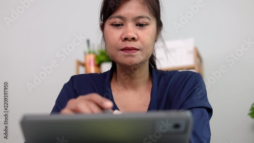 Female executive writing digital signatures on contract document via tablet display with electronic stylus pen while sitting at desk in elegant business office room location