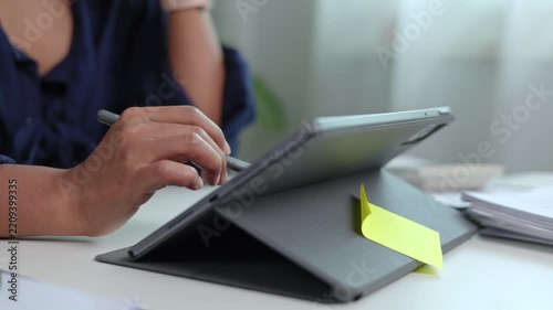 Detailed view of female hand drawing precise digital line artwork on tablet screen using stylus pen at work desk in contemporary corporate office setting environment room