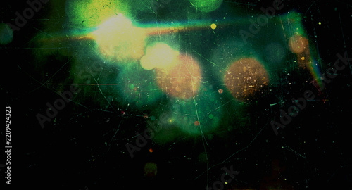 vintage light leak with glowing green and yellow bokeh, orange circles, rainbow light streaks, heavy scratches, dust particles and film grain texture on a black background for overlays and designs