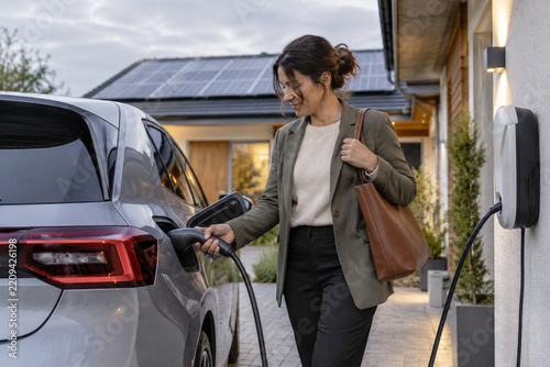 Generic electric car charging at home during calm evening hours in a solar suburban home driveway for home charging and renewable energy